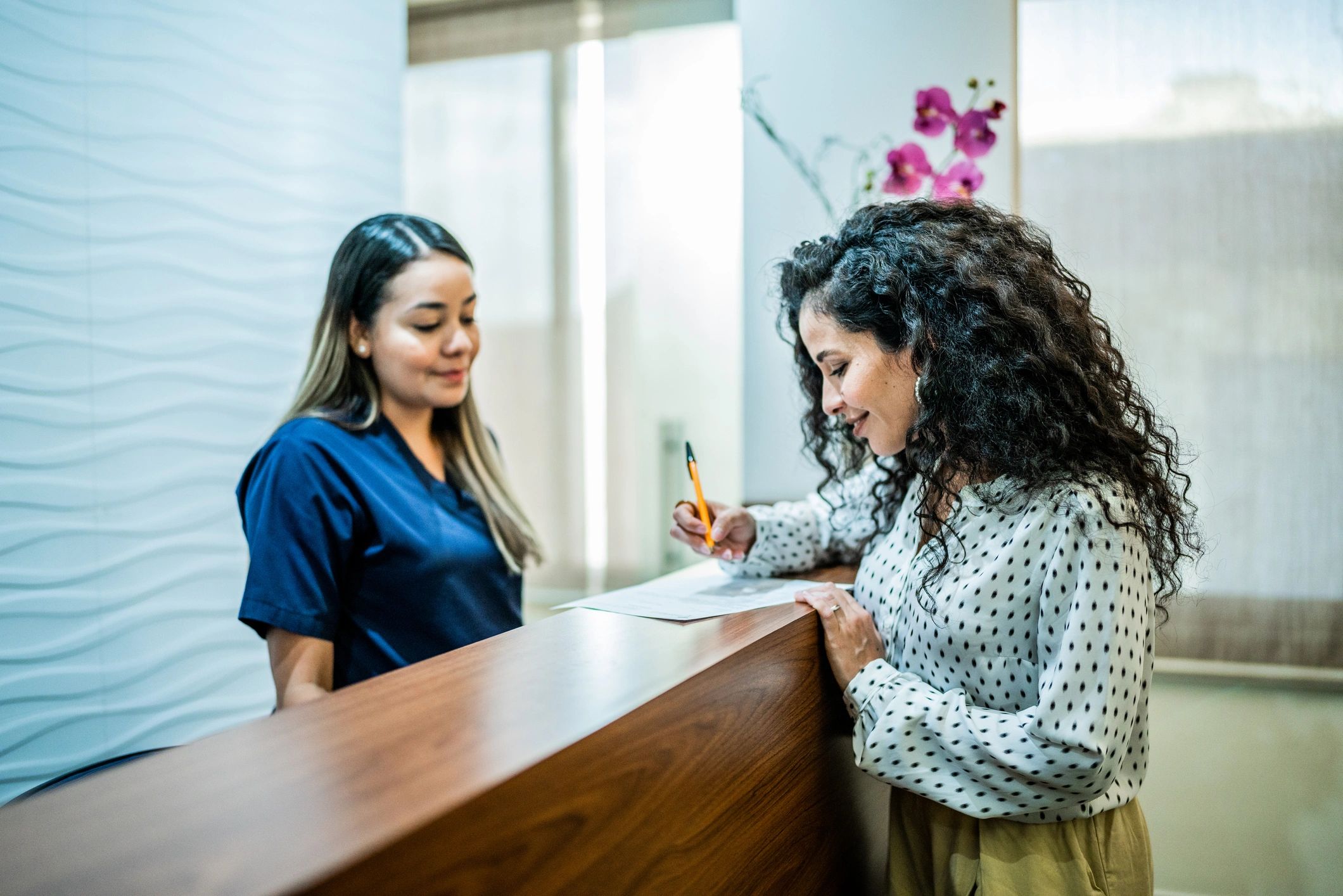 Client speaking with staff at a reception desk during a consultation