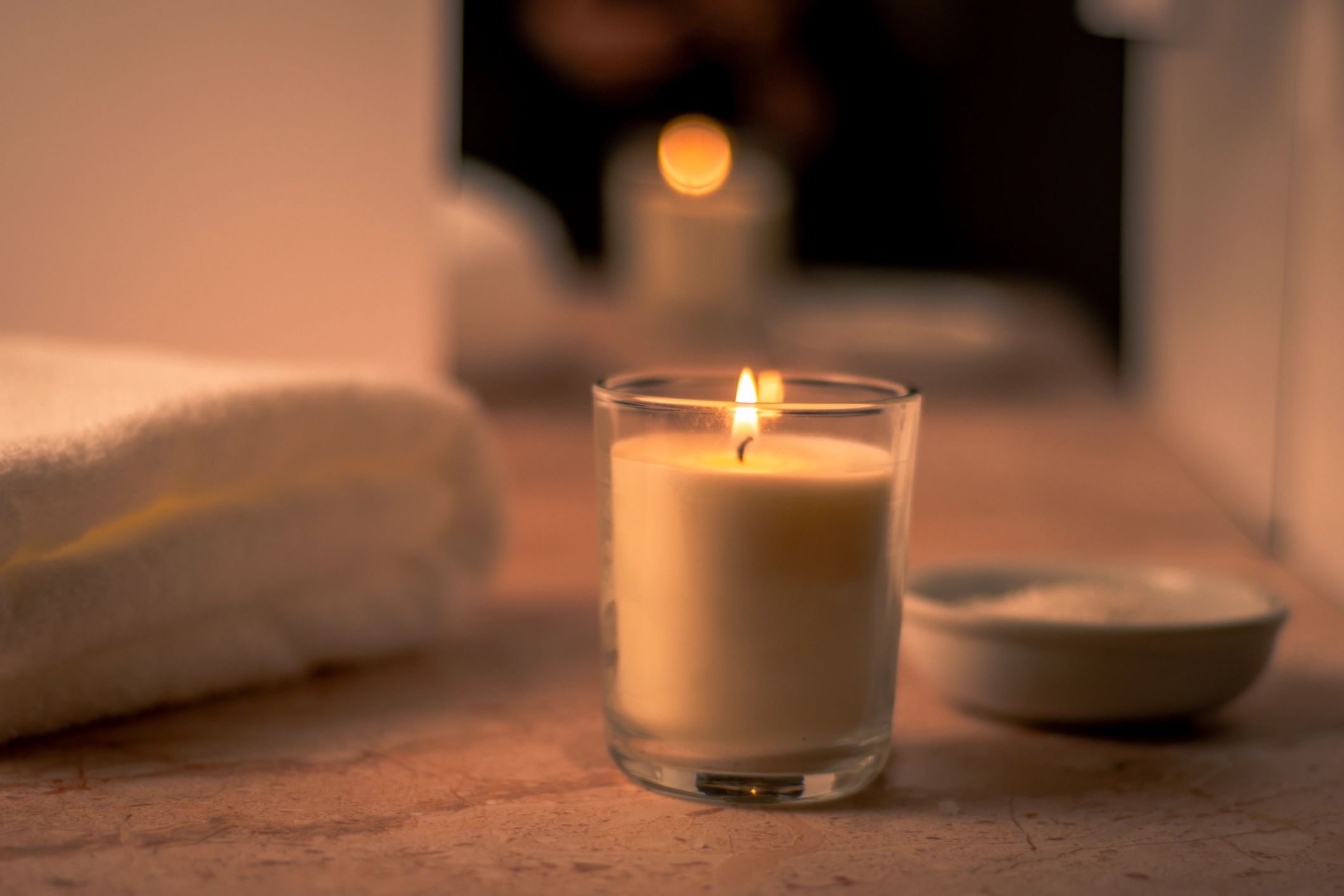 Warm candlelight spa scene with towel and bath salts